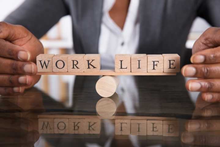 Woman holding the words 'work' and 'life' on a seesaw