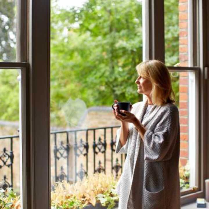 Middle aged women enjoying a cup of coffee looking out to her garden