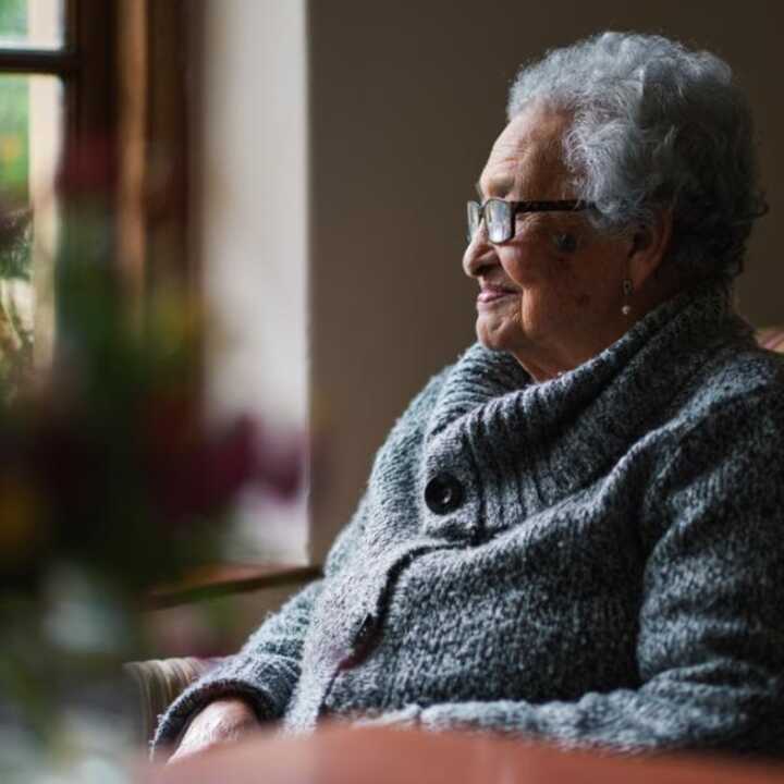 Elderly retired woman smiling, sat in a chair