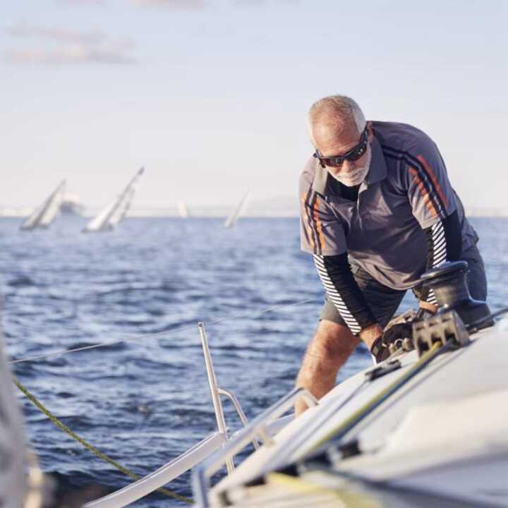 Elderly man enjoying his retirement sailing a boat in the sea