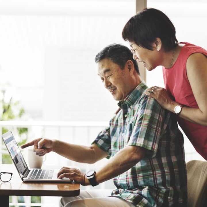 Middle aged couple happy at statistics on their laptop