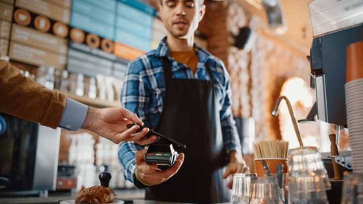 Customer in a coffee shop using their phone to pay