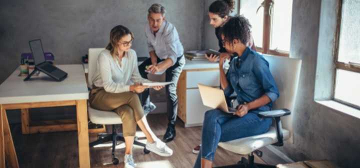 Group of four employees working together in a small office