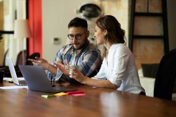 Two colleagues with laptops, having a discussion