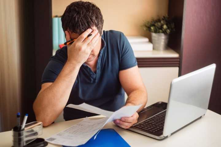 Worried man with a laptop looking at a bill