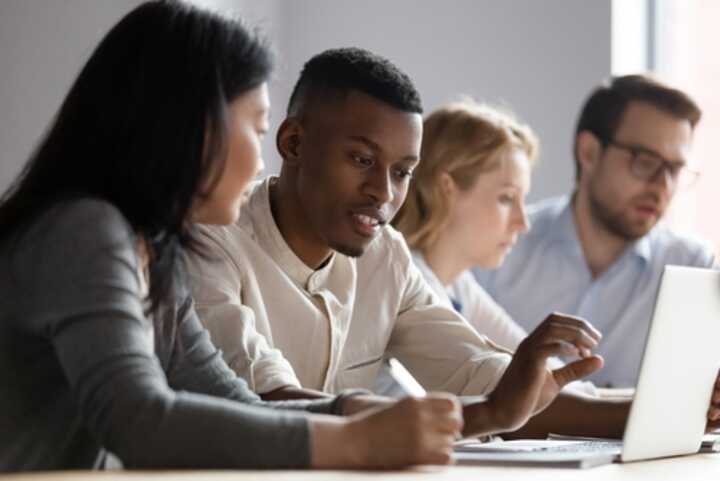 Four business colleagues working in pairs with a laptop