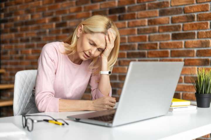 Middle-aged woman working at a laptop while unwell