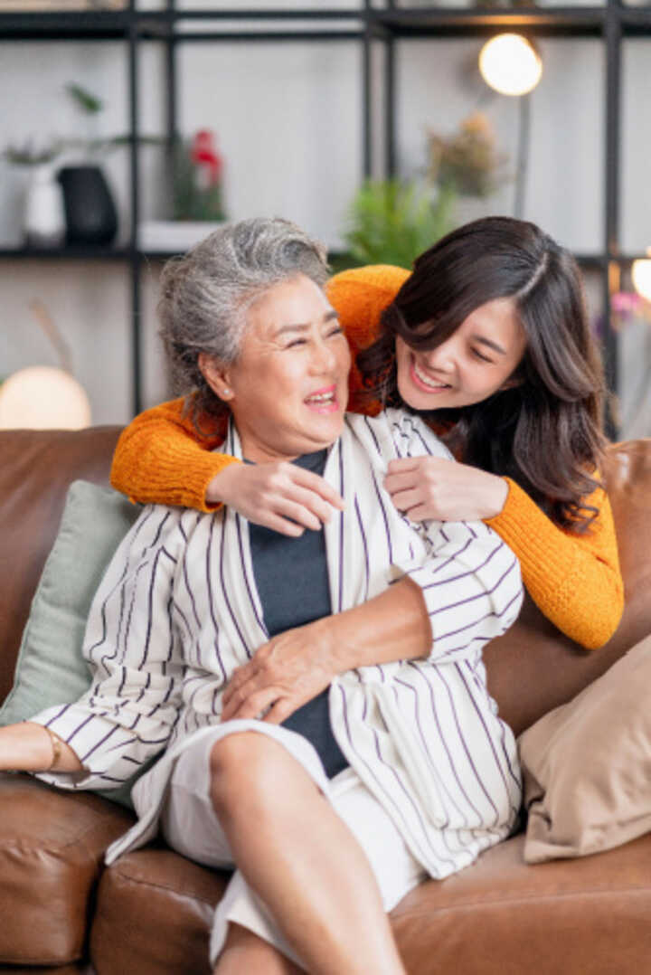 Mother and daughter hug on the sofa