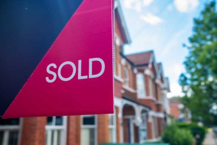 Estate agent's 'sold' sign with townhouses in the background