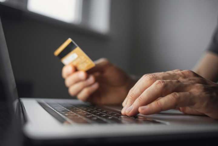 Man hand holding credit card and using laptop at home