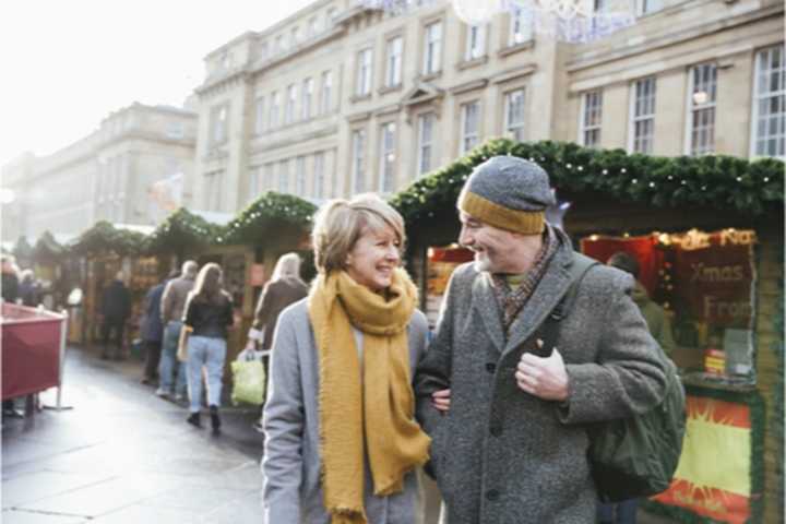 Couple in their 50s walking through a Christmas market