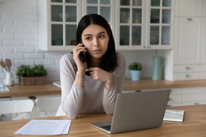 Young Asian remote worker talking on mobile phone