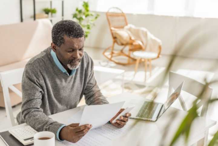 Man with laptop and calculator looking at paperwork