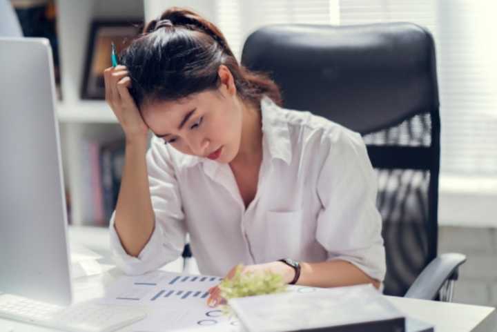 Business woman working at her desk, looking stressed