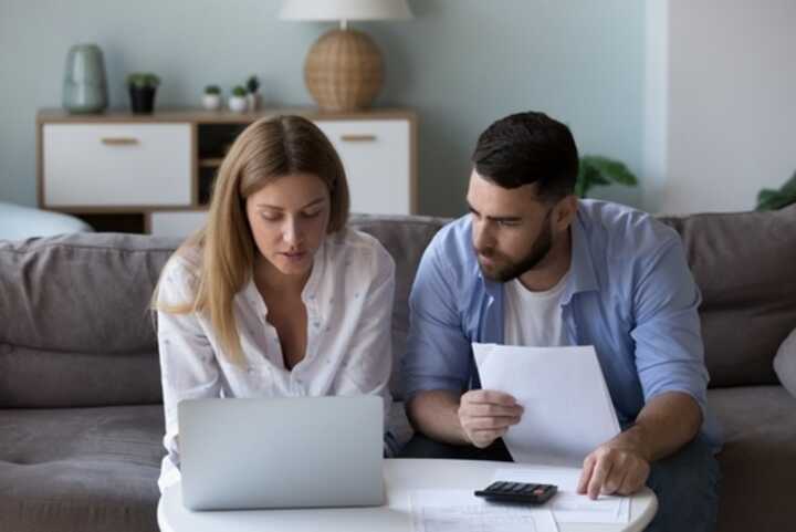 Young couple on sofa with laptop and paperwork