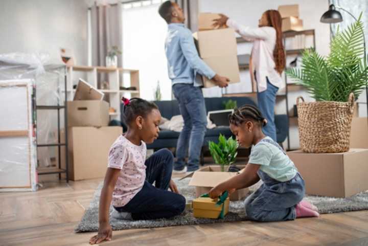 Parents packing boxes and children playing as family prepares to move home