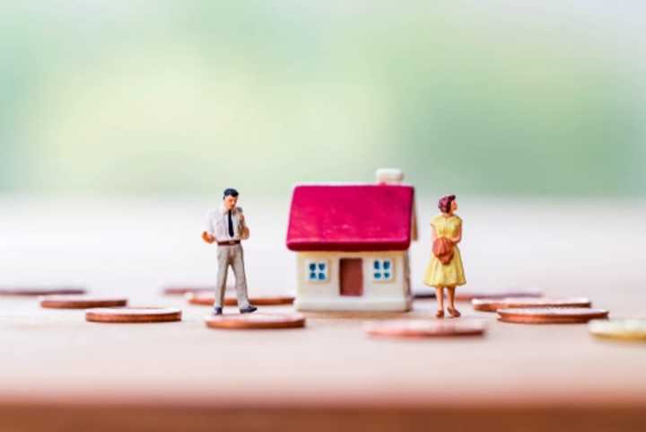 Model of a house with a divorcing couple and coins on the ground