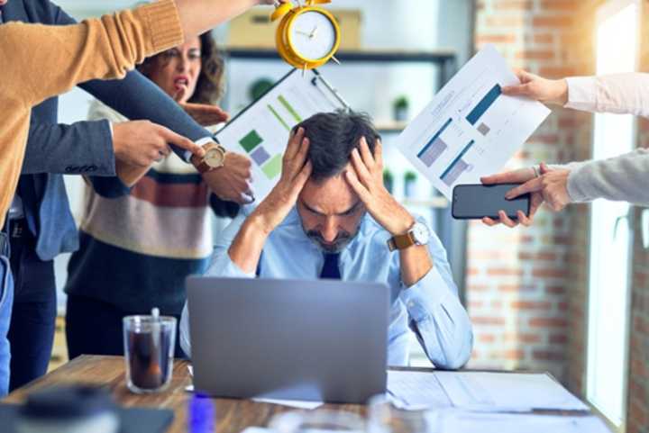 Male employee with laptop, feeling stressed by work pressures